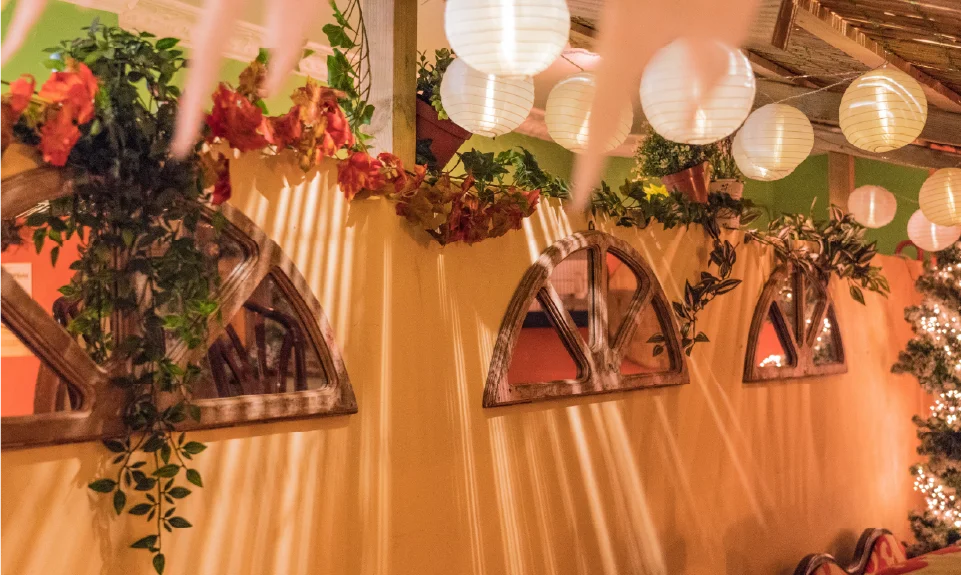 Achterste zaal, wanddecoratie met mediterrane spiegels, lampionnen en een rieten afdakje.